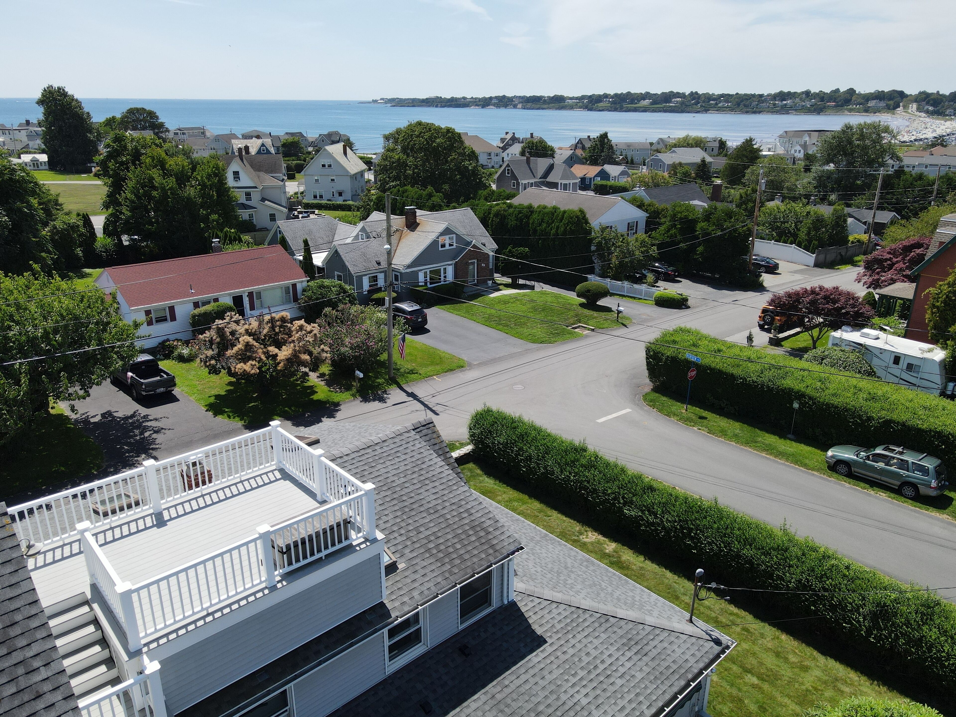 A residential area with houses, a road, and a view of the sea.