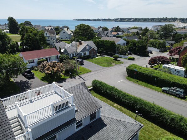 A residential area with houses, a road, and a view of the sea.