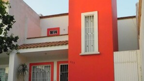 Un bâtiment à deux étages, doté d’une façade rouge et blanche, d’une petite fenêtre et d’un numéro de porte bien visible.