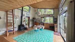 A spacious kitchen with a large window, a wooden ceiling, and a patterned rug.