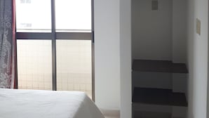 Ein Schlafzimmer mit Bett, Fenster, Treppe und Deckenventilator.