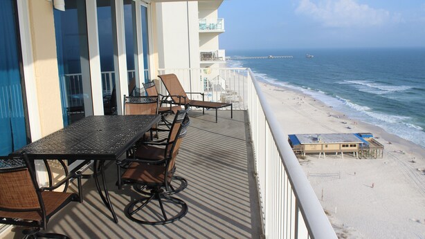 Un balcon avec une table et des chaises donnant sur une plage.