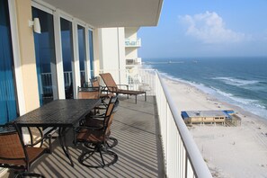 Ein Balkon mit Tisch und Stühlen mit Blick auf einen Strand.
