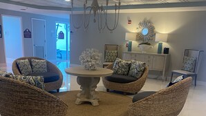 Un salon moderne avec des meubles en osier, une table ronde au centre et un lustre.