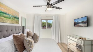 A bedroom with a bed, a ceiling fan, a window with curtains, a TV, and a dresser. - Quiet Scottsdale Retreat ~ 3BR ~ FirePit, Garage, EV Charging ~ Prime Location (Scottsdale)