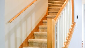 Eine Teppichstufen Treppe mit Holzwandleisten und einem Holnänder.