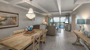 Un vaste espace de vie comprenant une table à manger en bois, un lustre et une grande fenêtre donnant sur l’extérieur.