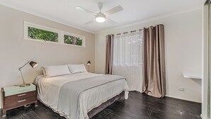 A bedroom with a bed, nightstands, a ceiling fan, and a window with curtains. - Charm & Character in the heart of Noosaville (Noosaville)