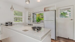 A modern kitchen with white cabinetry, a large island, a built-in oven, and a refrigerator. - Charm & Character in the heart of Noosaville (Noosaville)