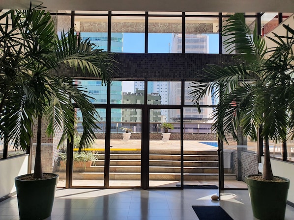 A view through a glass door with a staircase leading outside, surrounded by potted plants.