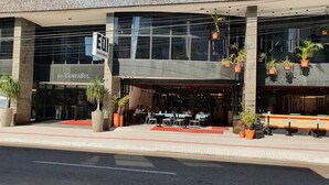 Een modern gebouw met een glazen gevel, een terras buiten en potplanten.