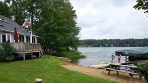 A lakeside property with a grassy yard, a dock, and a covered seating area.