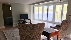A living room with a large window, a television, and patterned chairs.