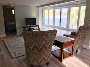 A living room with a large window, a television, and patterned chairs. - ~Baboosic Lake Waterfront Rental~ (Amherst)