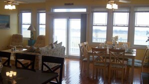 A dining area with a table and chairs, a sofa, and a view of the outdoors through large windows. - FEEL THE FUN!! BEACH/OCEAN FRONT Clean & Modern 3-BR w/ Pool, Direct Ocean Views (Wildwood Crest)