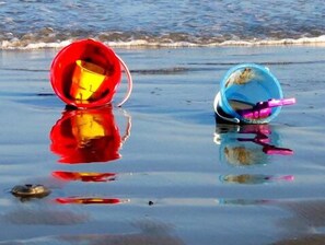 Two buckets on a wet beach with waves in the background.