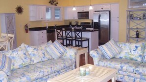 A compact living space with a kitchenette, two patterned sofas, a coffee table, and a small dining area. - FEEL THE FUN!! BEACH/OCEAN FRONT Clean & Modern 3-BR w/ Pool, Direct Ocean Views (Wildwood Crest)