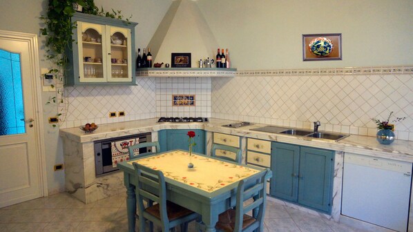 A kitchen with a dining table, chairs, cabinets, and a sink. - Sicilian villa with pool (Marsala)