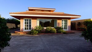 Una casa a due piani con tetto in tegole, ampie finestre e vialetto lastricato.