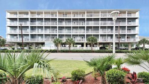 Un hotel de varios pisos con balcones, estacionamiento y jardines ajardinados.