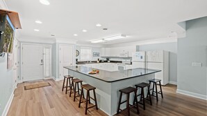 Una cocina moderna con una isla central, taburetes de bar y una barra desayunadora.