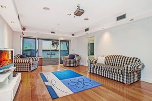 Relax in this stylish living room with a large flat-screen TV, two comfortable armchairs, and a balcony view.