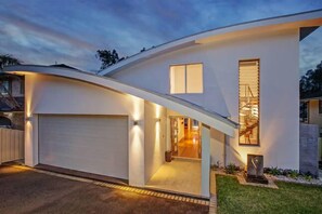Stunning home with a curved facade, prominent garage door, and beautifully landscaped outdoor area.