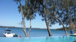 Una piscina azul cristalina con un bote al fondo, rodeada de árboles.