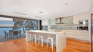 Una cocina moderna con una isla grande, taburetes de bar y vistas al mar.
