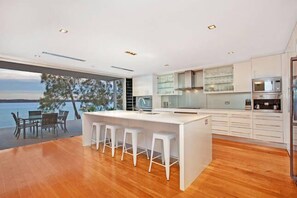 Enjoy meals in the kitchen with a central island and bar stools, offering a view of the outdoors and a body of water.