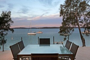 Enjoy a serene meal with a view of the sea from this outdoor dining area surrounded by tall pine trees.