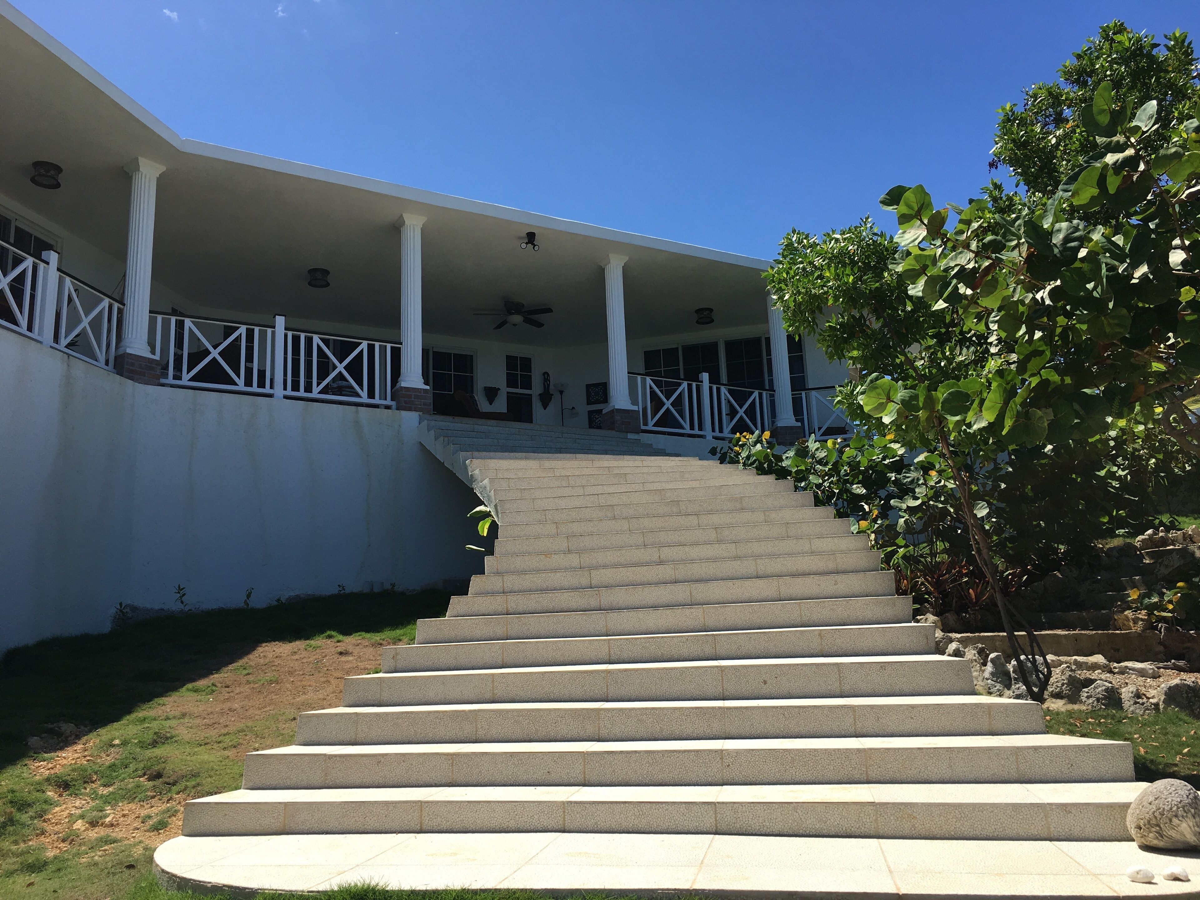 Un escalier extérieur en pierre menant à un bâtiment doté d’un porche couvert et de colonnes.