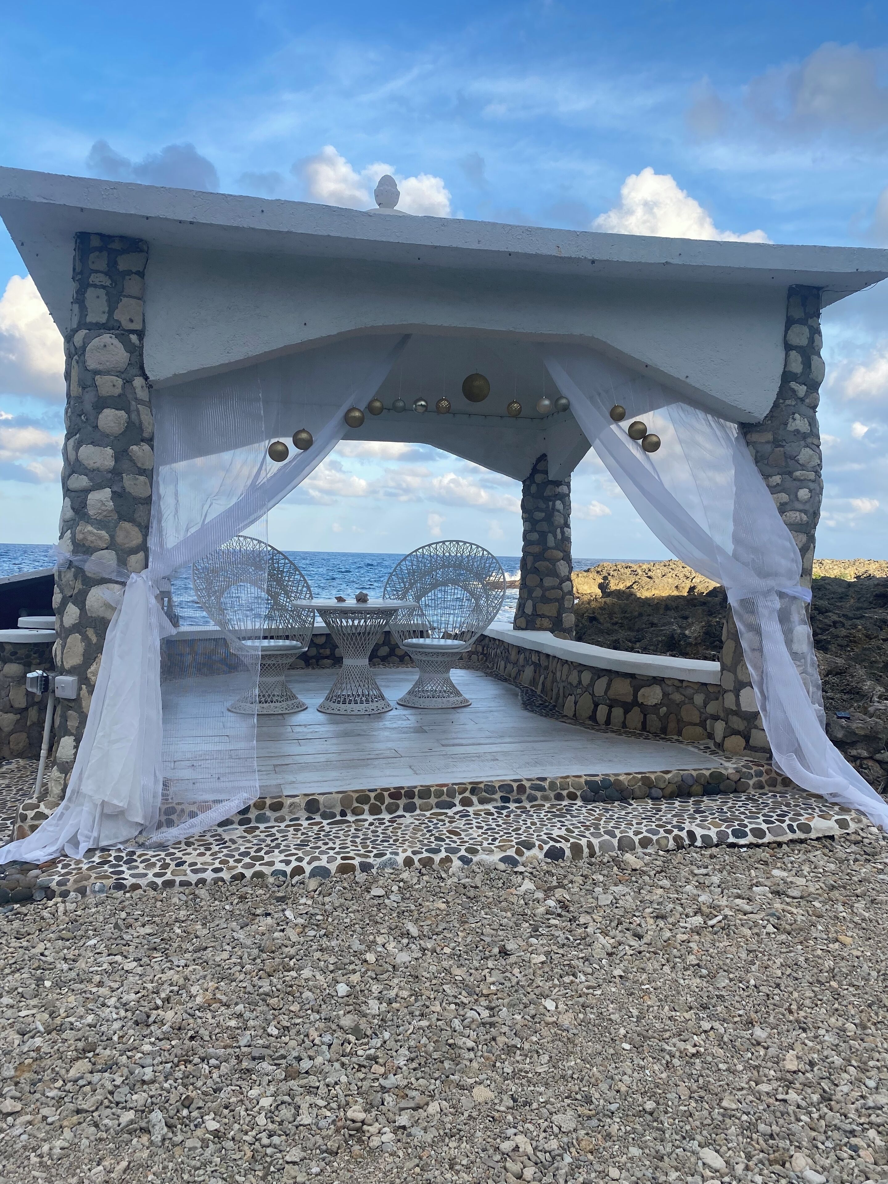 Un espace extérieur aménagé avec des sièges en pierre et en béton, offrant une vue sur la mer.