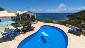 A swimming pool with a view of the ocean, a covered patio area with chairs, and a small table. - Gorgeous Private Pool And Ocean Views Await! (Christiansted)