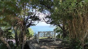 A bench overlooking a coastal view with dense foliage and a clear sky. - Gorgeous Private Pool And Ocean Views Await! (Christiansted)