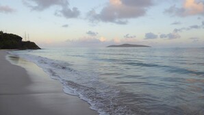 A beach with gentle waves, a distant island, and a clear sky. - Gorgeous Private Pool And Ocean Views Await! (Christiansted)