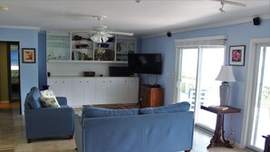 A living room with a blue sofa, a television, and a ceiling fan. - Gorgeous Private Pool And Ocean Views Await! (Christiansted)