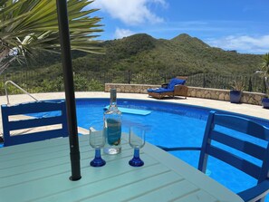 Zona de piscina con una mesa, una botella de ron Cruzan Coconut y dos vasos.