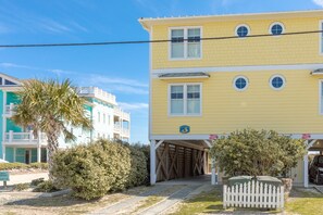 A multi-story yellow building with a covered entrance and a white picket fence. - The Lazy Loggerhead - 4 BR Duplex w/ Great Covered Porch! (Topsail Beach)