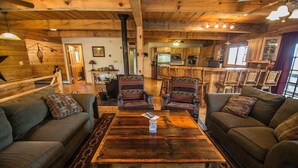 Ein gemütliches Blockhauss-Interieur mit einem Holzesstisch, zwei Sofas und einer Küchenzeile.