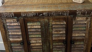 Un coffre en bois rustique portant l’étiquette « Perch », placé sur une table devant laquelle on aperçoit, en arrière-plan, une photographie encadrée d’un bâtiment.