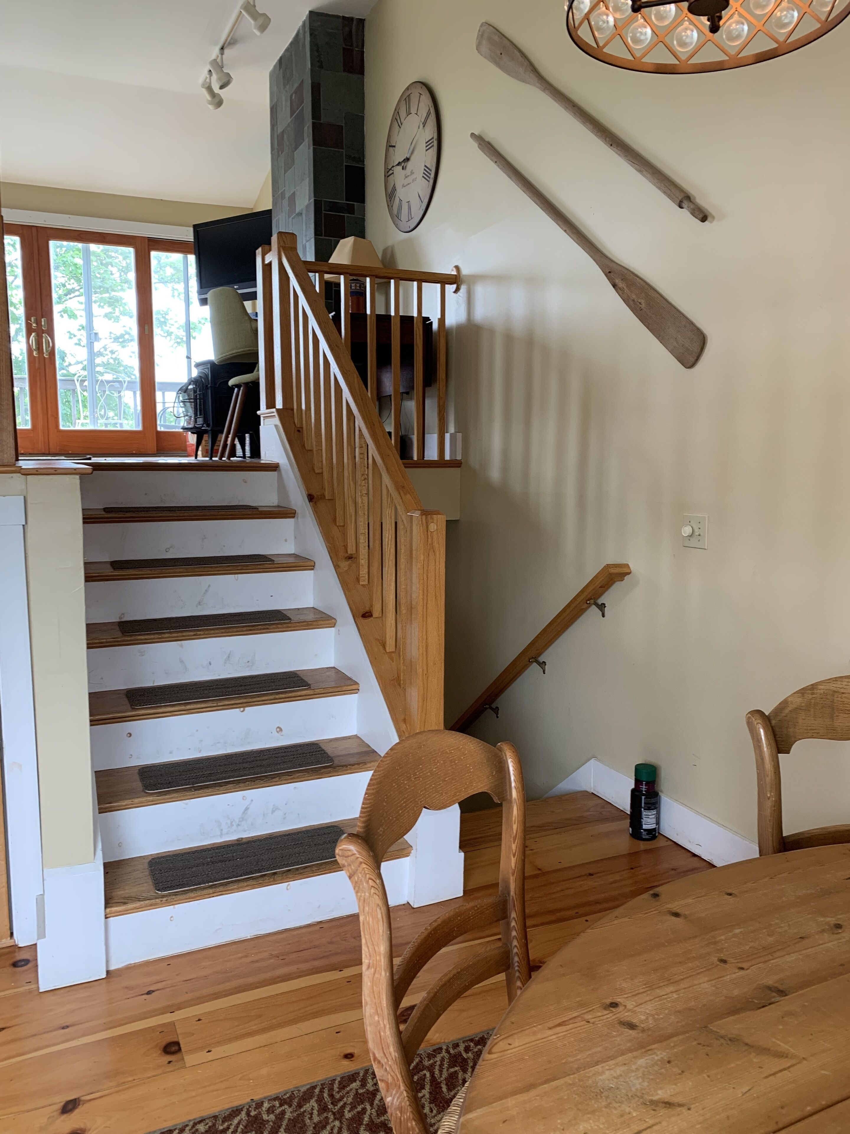A staircase with wooden railings leading to a landing area with a clock and a television.