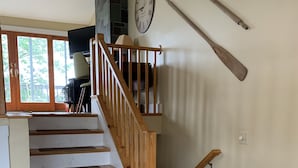 Un escalier avec des rampes en bois menant à un palier où se trouvent une horloge et un téléviseur.