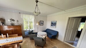 A cozy living room with a wooden dining table, a blue sofa, and a small rug.