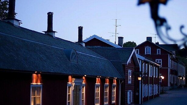 A row of traditional red buildings with a dark roof, likely a hotel or inn, with a street in front.