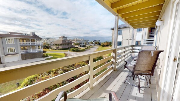 Varanda com cadeira, guarda-corpo de madeira e vista para casas vizinhas.