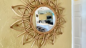 Een spiegel aan de muur met een rond frame van gevlochten materiaal.