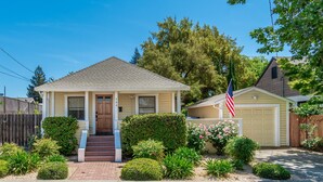 A single-story house with a front porch, a garage, and a well-maintained front yard with various plants and flowers.