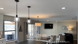 A modern kitchen with a dining area, a TV mounted on the wall, and a sign indicating 'Lake Boats Cabins'.