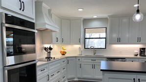 A modern kitchen with white cabinetry, stainless steel appliances, and a window providing natural light.